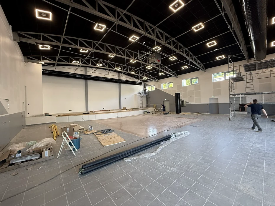 Magasin de vêtements masculins moderne avec mannequins en costume, présentoirs centraux de chemises pliées et penderies murales